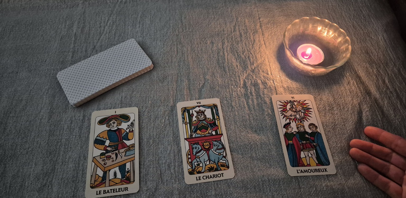 Une main présente trois cartes du Tarot de Marseille